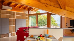 A cozy dining area with a wooden ceiling, a red sofa, and a table set with breakfast.