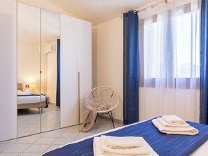 Een hotelkamer met een bed, een stoel, een kledingkast en een raam met gordijnen.
