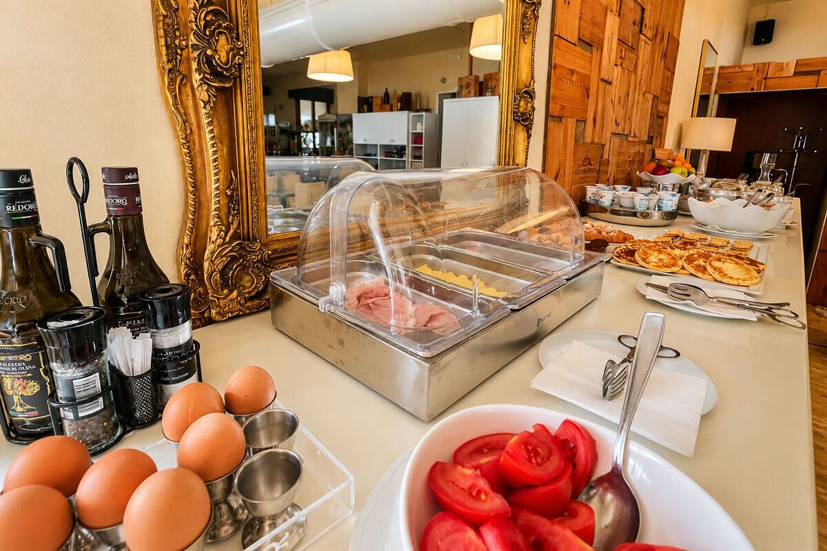 A breakfast buffet with various food items, a wine selection, and a decorative mirror.