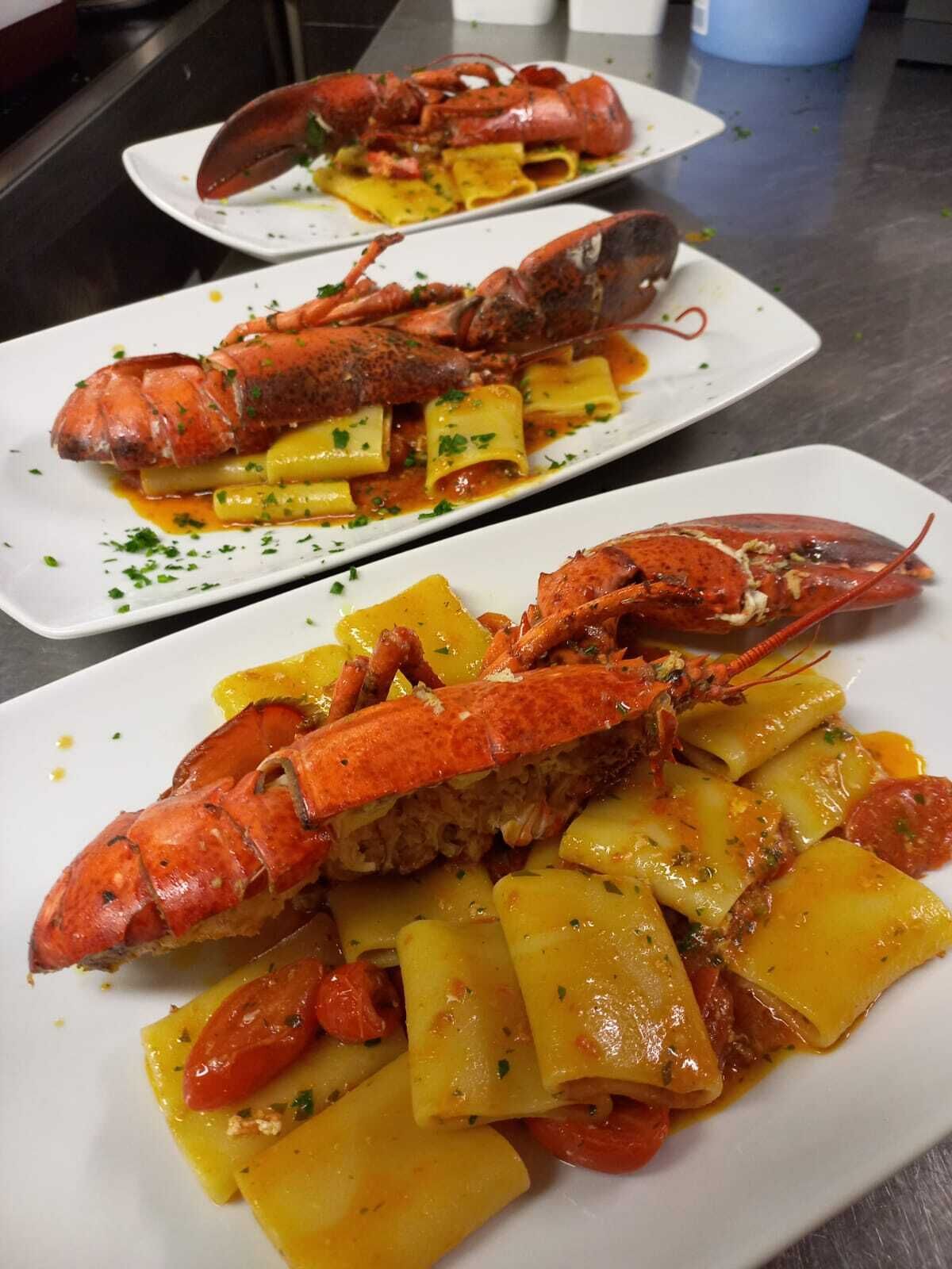 Hummerret med kartofler og tomater på en hvid tallerken.