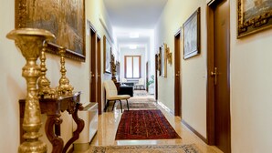 A hallway with a patterned carpet, a chair, and a table with a vase. - Locanda al Santuario (Peschiera del Garda)