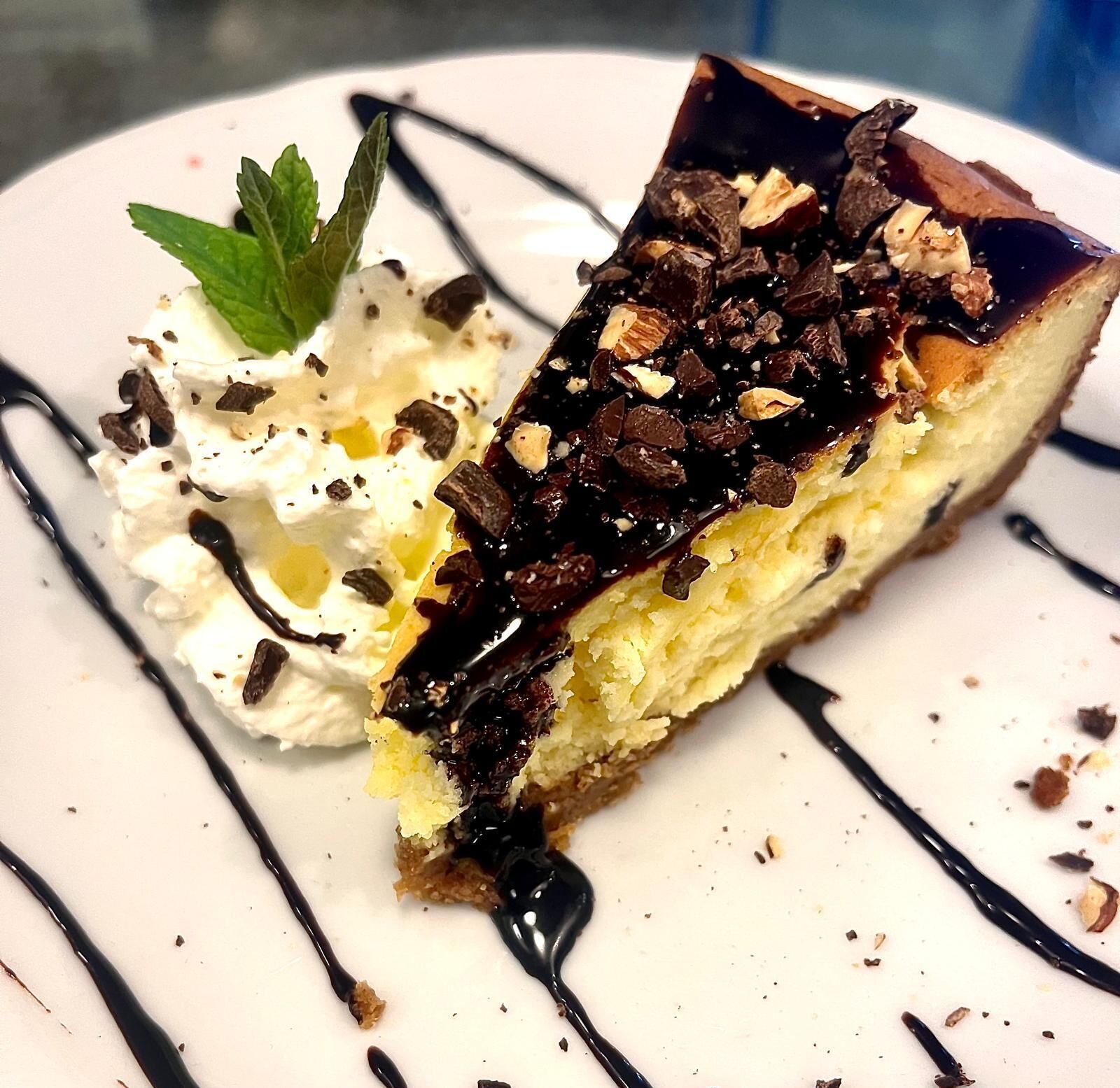 Een stuk taart met slagroom en chocoladeschaafsel op een bord.