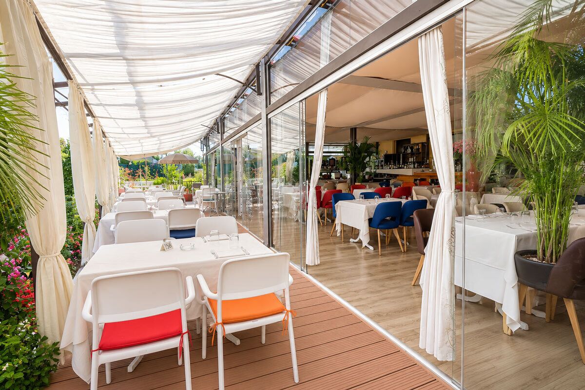 An outdoor dining area with tables and chairs, a covered walkway, and a view of the interior.
