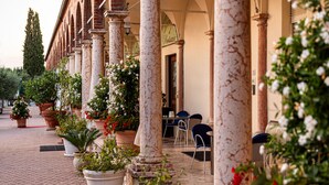 A courtyard with columns, potted plants, and outdoor seating. - Locanda al Santuario (Peschiera del Garda)