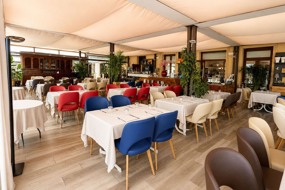 Un restaurant avec plusieurs tables et chaises, un coin bar et un buffet en bois à l’arrière-plan.