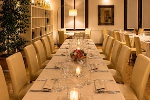 Una larga mesa de comedor dispuesta con sillas, velas y un centro de mesa.