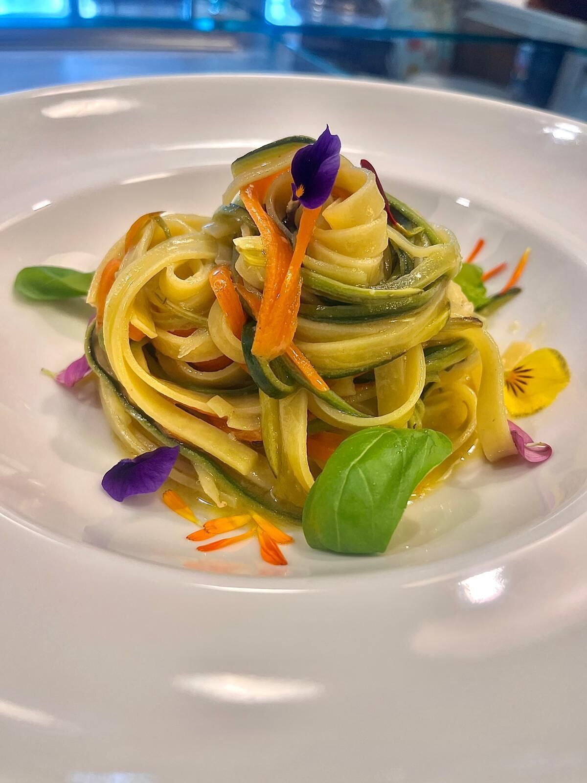A plate of pasta with vegetables and flowers.