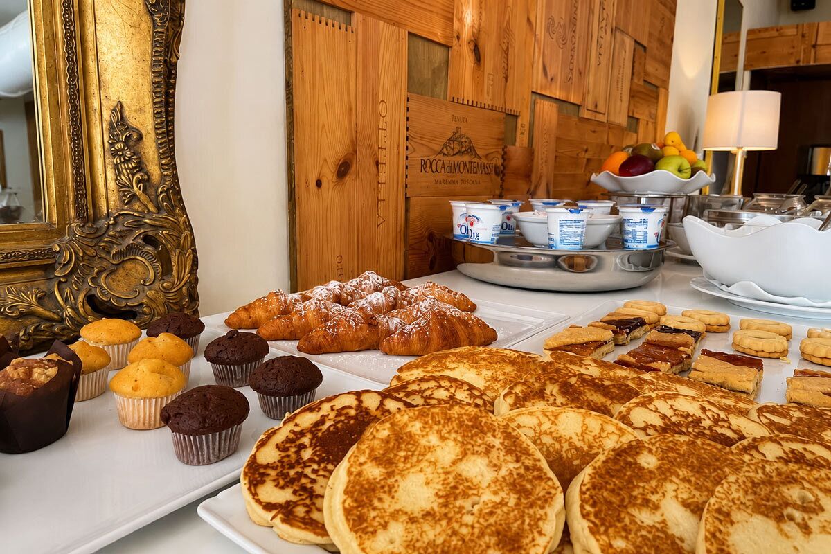 Un bufé de desayuno con bollería, magdalenas y un bol de fruta.