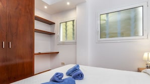 Une chambre d’hôtel avec un lit, une armoire en bois, une fenêtre donnant sur un beau paysage et une table de chevet avec une lampe.