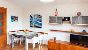 Un salon moderne comprenant un coin repas, un téléviseur et des œuvres d’art accrochées au mur.