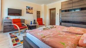A bedroom with a bed, two red chairs, a desk, a TV, and a painting on the wall. - Nice apartment for 10 people with private pool, WIFI, A/C, TV and balcony (Marcali)