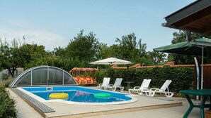 A swimming pool with a covered area, lounge chairs, and a swing chair. - Nice apartment for 10 people with private pool, WIFI, A/C, TV and balcony (Marcali)