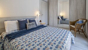 Un dormitorio con cama, una silla, un armario y un espejo.