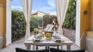 Un espace de restauration en plein air avec une table dressée pour deux personnes, entouré de verdure et d’un mur en pierre.