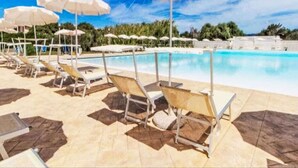 Un espace piscine équipé de chaises longues et de parasols.