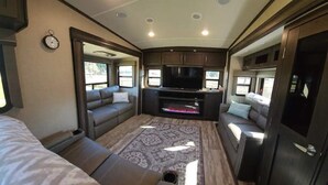 A cozy RV interior with a sofa, a flat-screen TV, and a fireplace. - Luxurious 37' 5th Wheel. Enjoy all the fun of Glamping  (Forks)