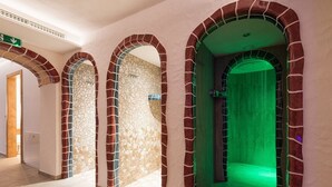A hallway with three arched doorways, each with a mosaic wall and a green-lit interior.