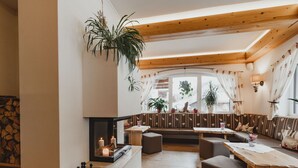 Ein gemütliches Interieur mit Kamin, Holzbalken und einer Sitzecke mit Blick ins Freie.