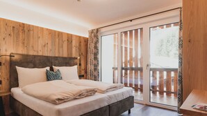 A bedroom with a wooden headboard, a bed with beige bedding, a nightstand, and a wooden floor. - Lovely apartment for 6 guests with WIFI, TV, balcony and panoramic view (Dienten Am Hochkönig)