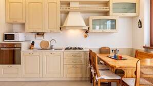 A kitchen with wooden cabinets, a microwave, a sink, and a dining table with chairs. - Lovely apartment for 4 people with WIFI, TV, balcony and pets allowed (Vendrogno)