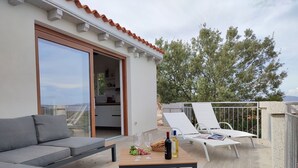 Ett modernt utomhusområde inrett för avkoppling, med en soffa, fåtöljer och ett bord dukat med vinglas och en vinflaska.