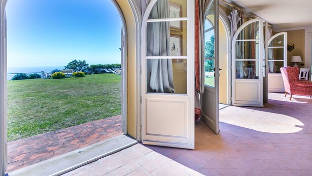A room with large arched windows, a view of a grassy area, and a red chair. - Beautiful private villa with WIFI, private pool, A/C, TV, patio, pets allowed and panoramic view (Montecatini)