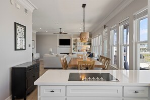 A modern kitchen with a central island, dining area, and a view of the outdoors.