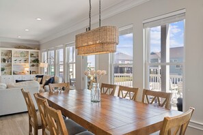 A spacious dining area with a wooden table and chairs, large windows, and a hanging woven light fixture. - Unbeatable LOCATION, first row, Oceanfront! (Bolivar Peninsula)