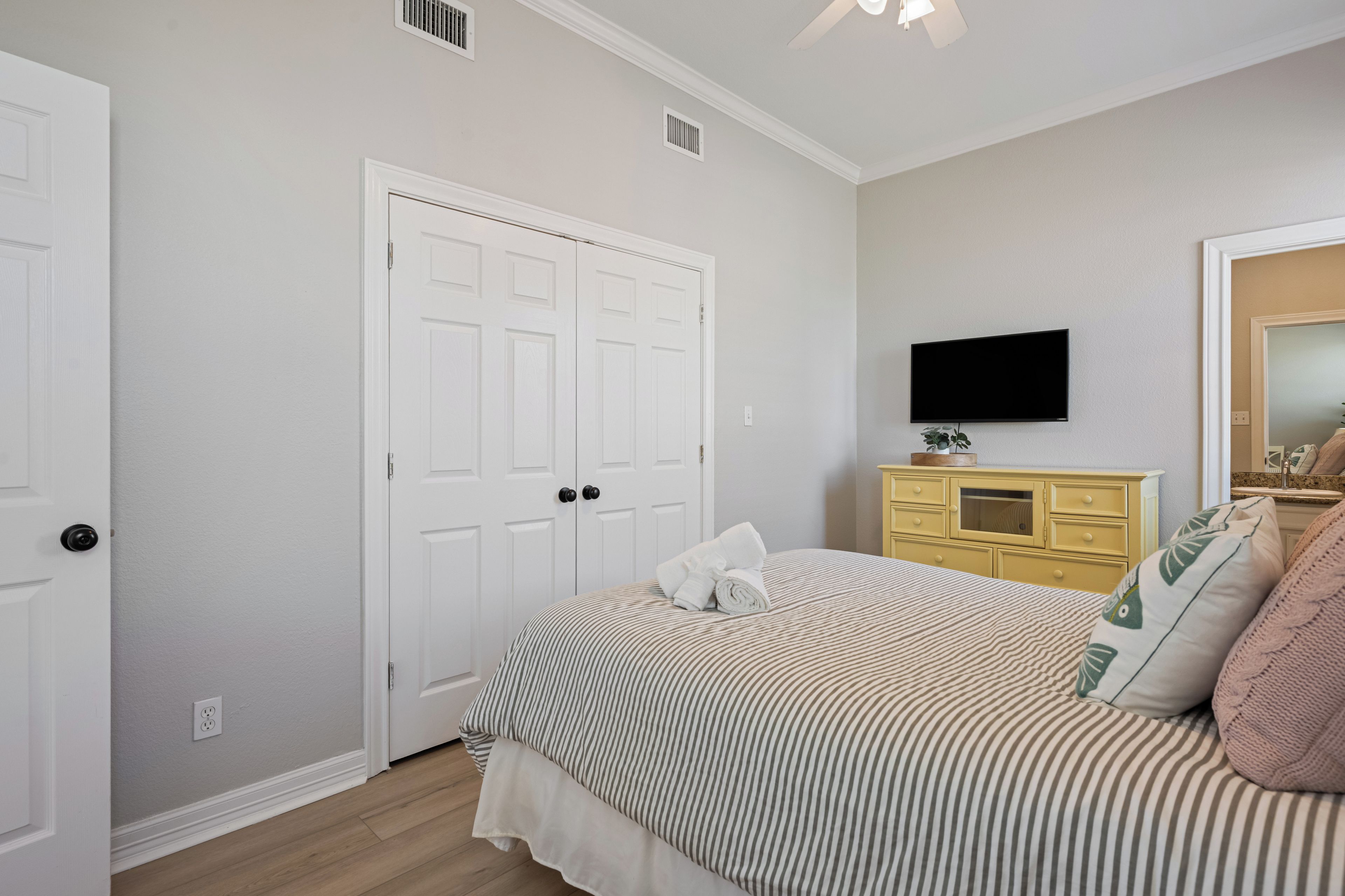 Une chambre à coucher avec un lit, une commode, un téléviseur et une porte.