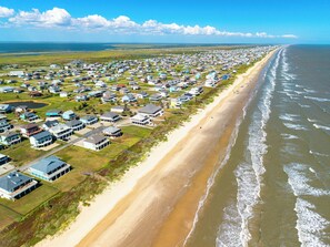 A coastal residential area with houses along the beach, a clear sky, and a view of the ocean. - Unbeatable LOCATION, first row, Oceanfront! (Bolivar Peninsula)
