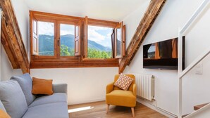 Ein Zimmer mit Holzboden, einer Couch, einem Sessel und einem Fernseher.