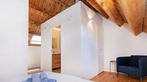 Ein Schlafzimmer mit einem Bett, einem blauen Sofa und einer Holzbalkendecke.