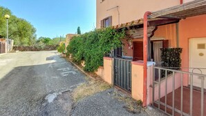 Un edificio de dos pisos con fachada roja, una entrada con reja y un pequeño porche.