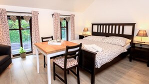 Una camera da letto con un letto di legno, un tavolo di legno con sedie e una finestra con tende.