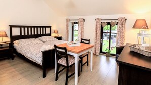 A bedroom with a bed, a wooden table, two chairs, a nightstand, a lamp, and a window with curtains. - Cosy apartment for 2 guests with WIFI, TV and terrace (Nový Bor)