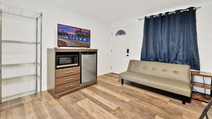 Habitación con kitchenette, sofá, televisión y ventana con cortinas.