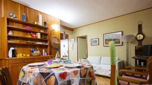 A cozy living room with a dining area, wooden furniture, and a quilt-covered table.