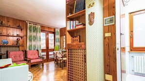 A cozy living room with wooden furniture, a bookshelf, and a decorative wall panel.