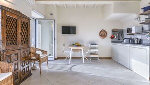 A compact kitchen with white cabinets, a microwave, and a kettle. There is a dining area with a table and chairs, and a large wooden cabinet with intricate patterns. - Cosy apartment for 2 people with WIFI, A/C, balcony and pets allowed (Marciana)