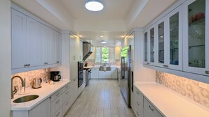 A modern kitchen with white cabinetry, a stainless steel refrigerator, and a built-in oven.