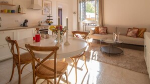 Eine moderne Küche mit weißen Schränken, einem Esstisch mit Stühlen und einem Wohnbereich mit einer Couch und Couchtisch.