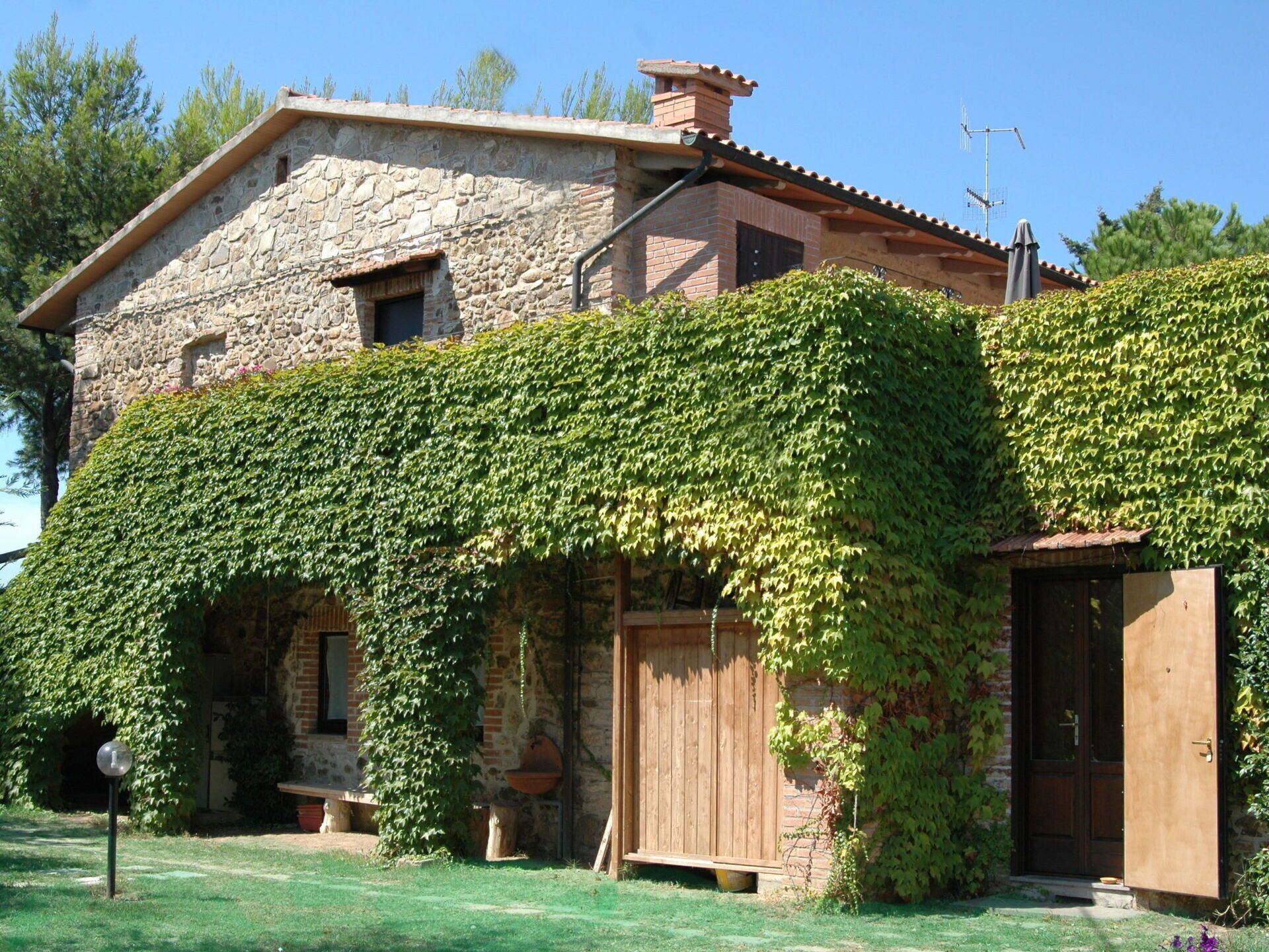 Une maison en pierre avec une porte en bois et une petite construction en bois sur la droite.