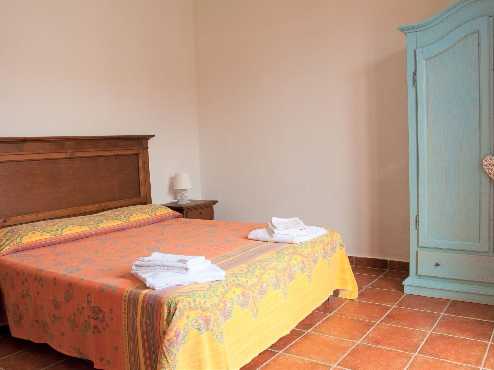 Une chambre à coucher avec un lit, une table de chevet, une lampe et une armoire.