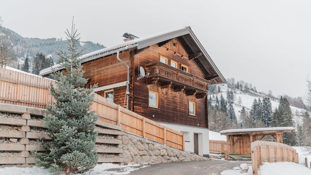 Una cabaña de madera con una escalera de piedra, una terraza de madera y un paisaje cubierto de nieve.