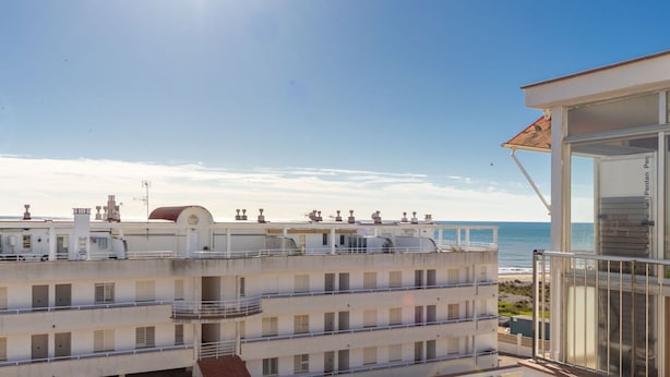 Un immeuble à plusieurs étages doté de balcons donnant sur une plage.