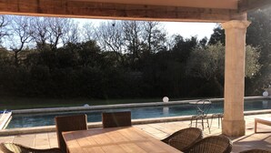 An outdoor patio with a wooden table and wicker chairs, overlooking a swimming pool. - Bastide Provencale 15mn au Nord Daix en Provence (Meyrargues)