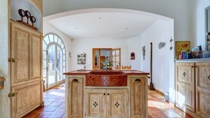 A spacious kitchen with a large island, wooden cabinets, and a tiled floor. - Bastide Provencale 15mn au Nord Daix en Provence (Meyrargues)