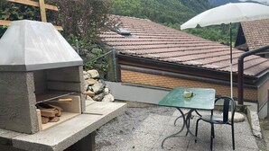 En uteplats med en grill, ett bord och stolar.