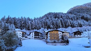 A snow-covered mountain resort with multiple chalet-style buildings, a ski slope, and dense forest. - Lovely apartment for 5 guests with WIFI, TV, terrace and pets allowed (Ischgl)