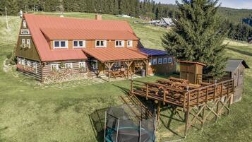 Un chalet rustique avec un toit rouge, une façade en bois et un petit chalet attenant.